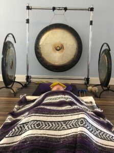 Photo of yoga practioner laying under blanket next to a gong.