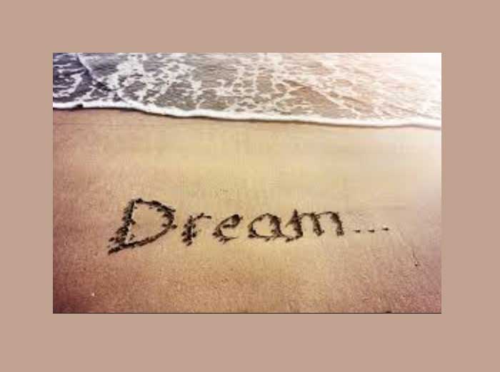Photo of the word 'Dream' written in the sand on a beach.