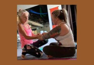 Photo of Wendy Santiago instructing a student of yoga.